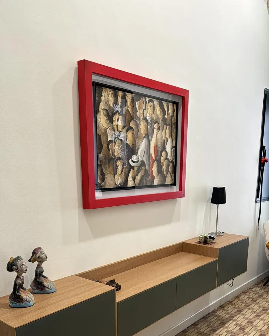 Cuadro enmarcado en un marco rojo intenso, sobre un mueble flotante y suelo de mosaico