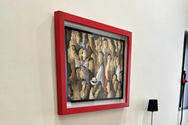 Cuadro enmarcado en una moldura roja de madera, colgado sobre un mueble flotante en un salón