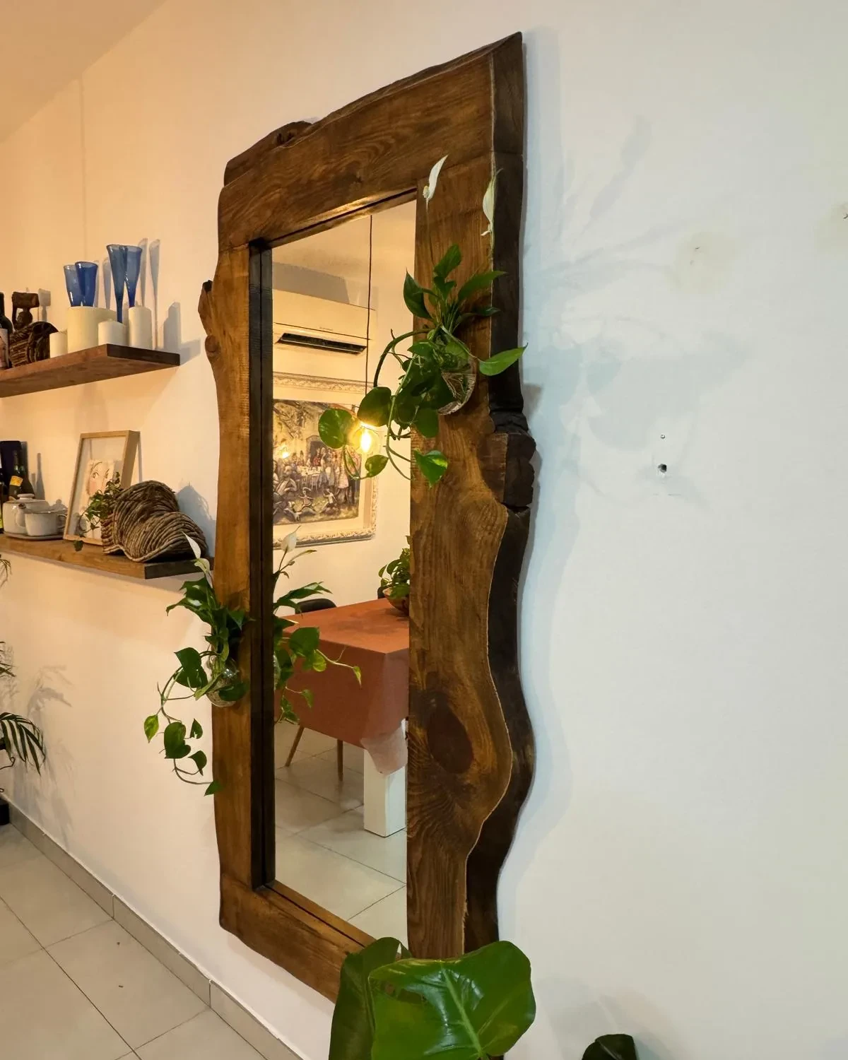 Espejo de cuerpo entero con marco de madera maciza de borde natural, en un recibidor con plantas