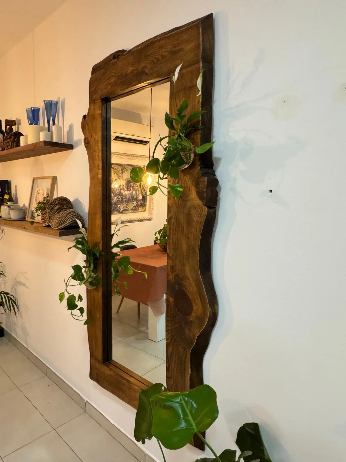 Espejo de cuerpo entero con marco de madera maciza de borde natural, en un recibidor con plantas