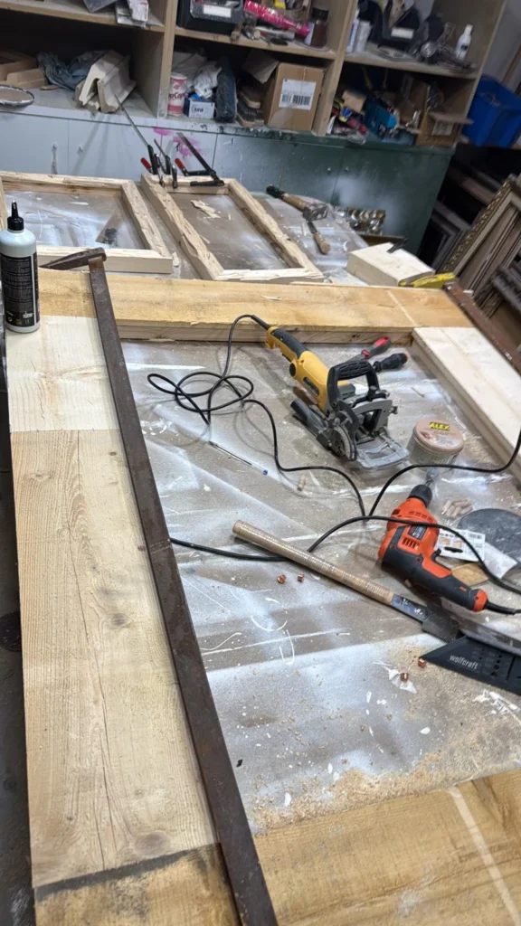 Tablones de madera reciclada y sierra circular sobre el banco, durante la fabricación de un marco a medida